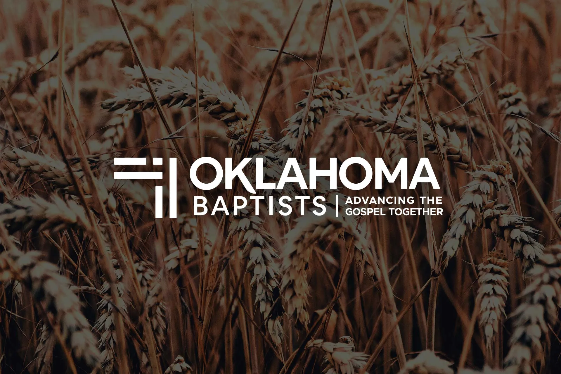The Oklahoma Baptists logo over an image of wheat in an Oklahoma field.